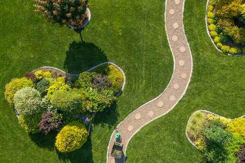a person is walking down a path in a garden